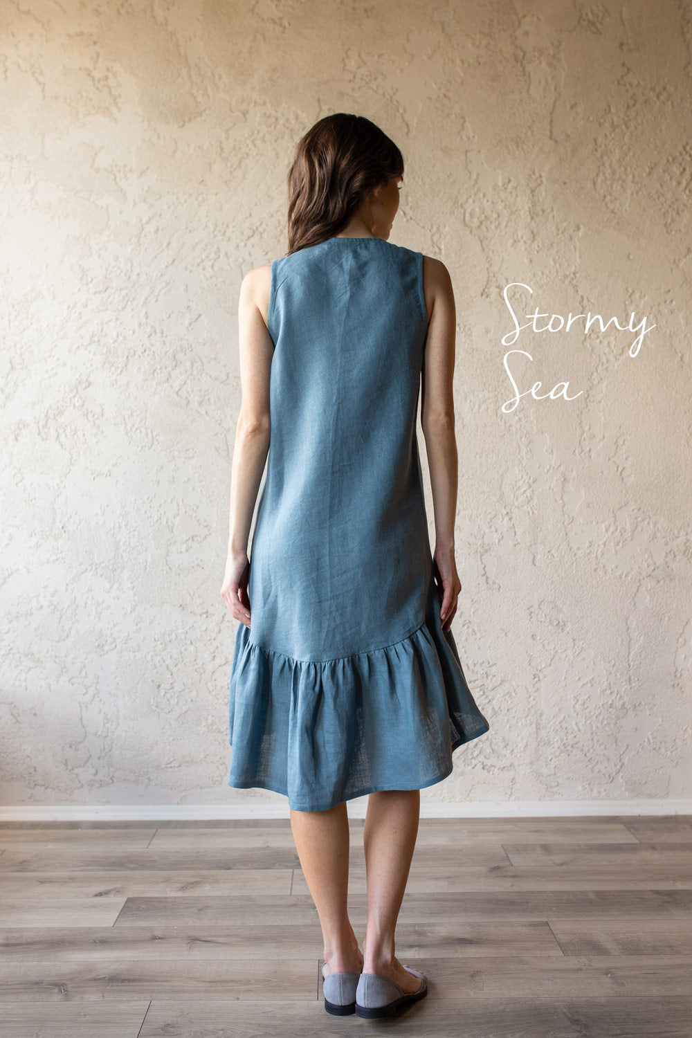 Woman wearing a blue natural linen dress with 'Stormy Sea' text on a plain background