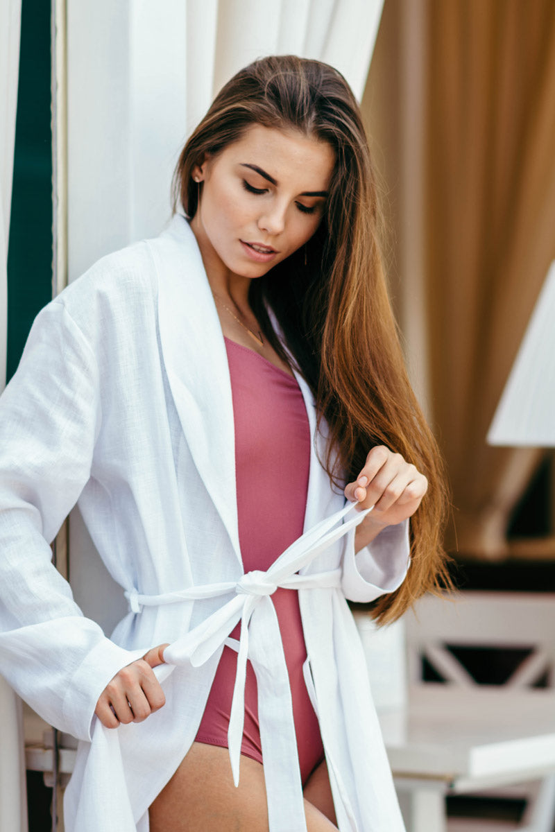 Woman wearing a pure white linen bathrobe, comfortable women’s dressing gown.