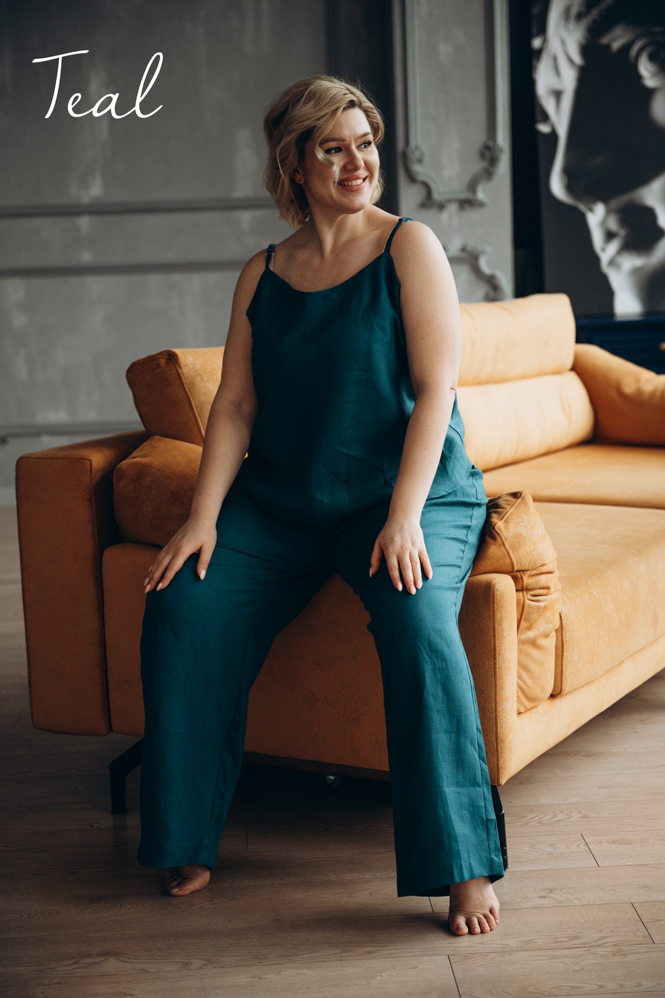 Plus size woman in teal washed pyjajmas sitting on a brown couch