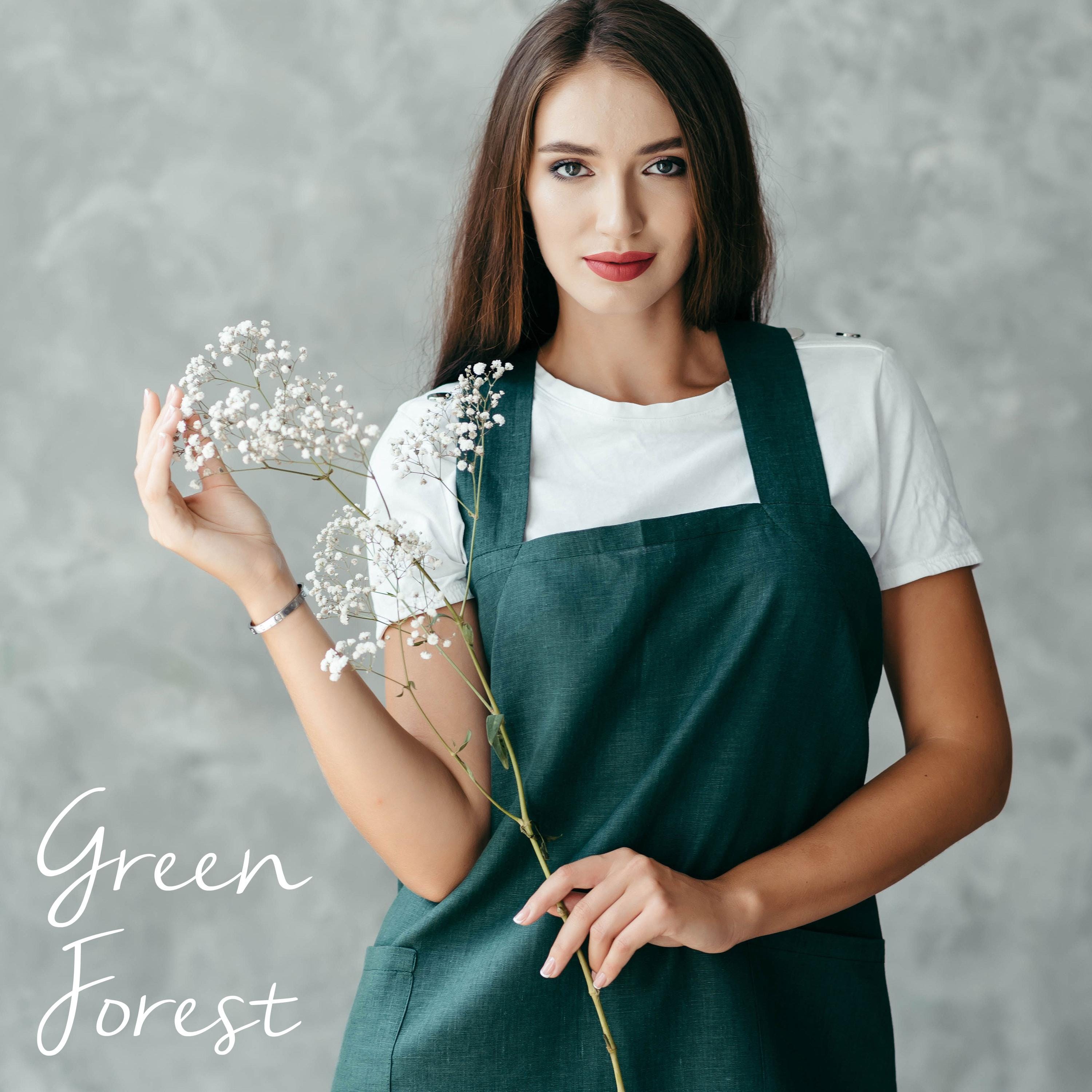 Woman wearing green forest linen pinafore apron with pockets.
