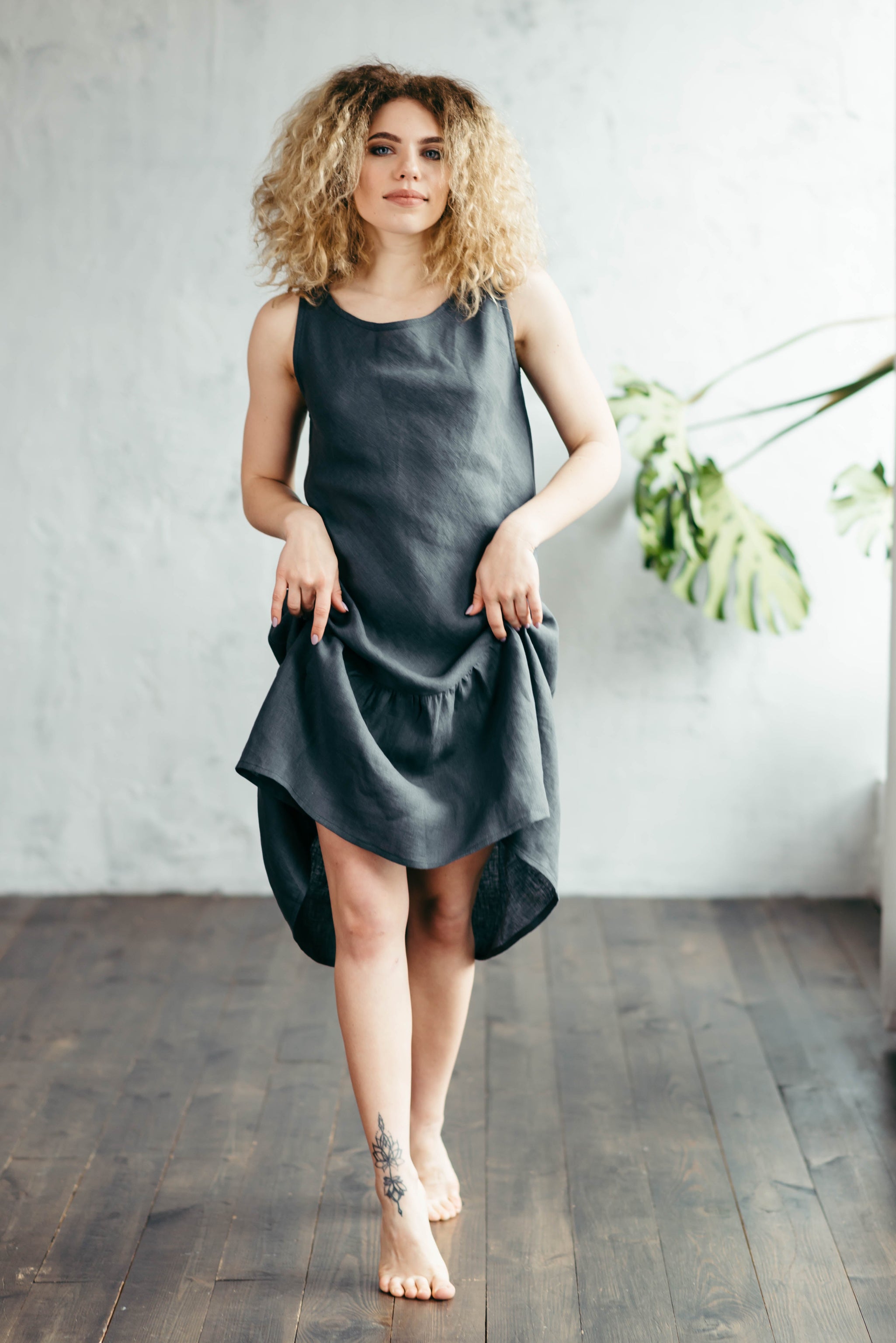 Woman wearing a dark gray lined day dress standing by the window