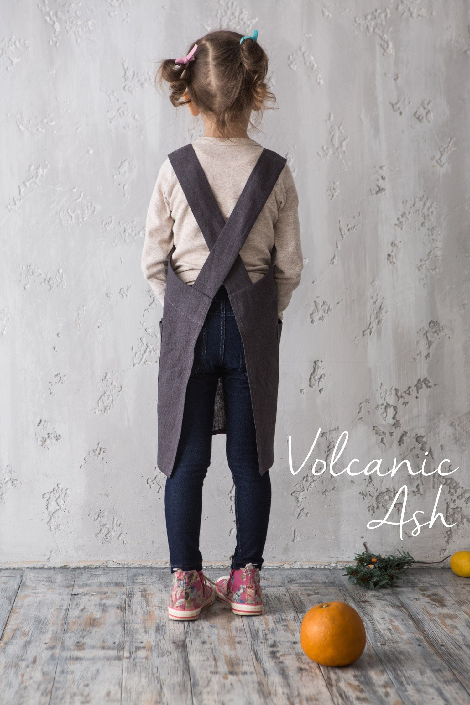 Child wearing a dark gray linen pinafore apron