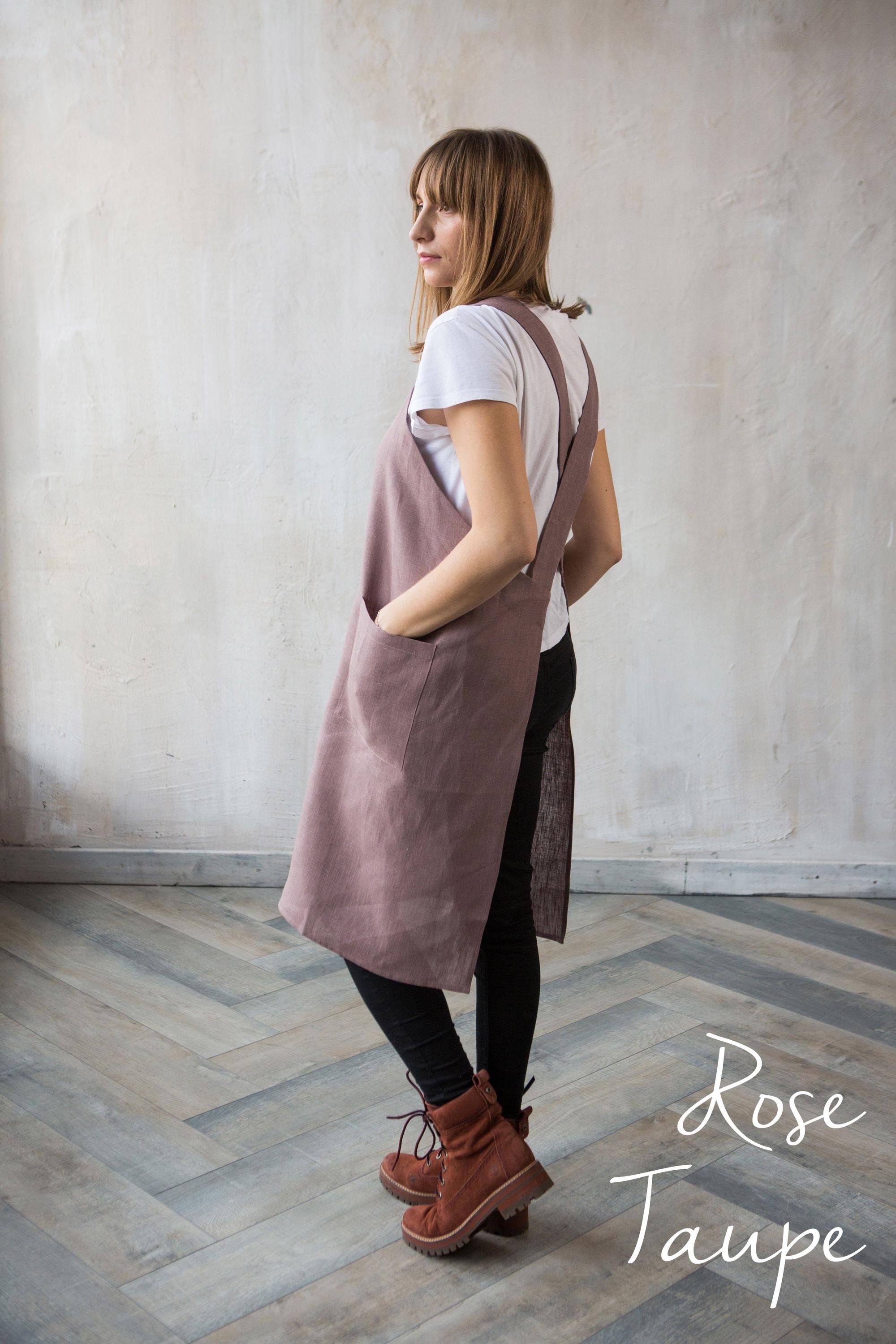 Woman wearing a rose taupe linen smocgk apron in a minimalistic studio setting