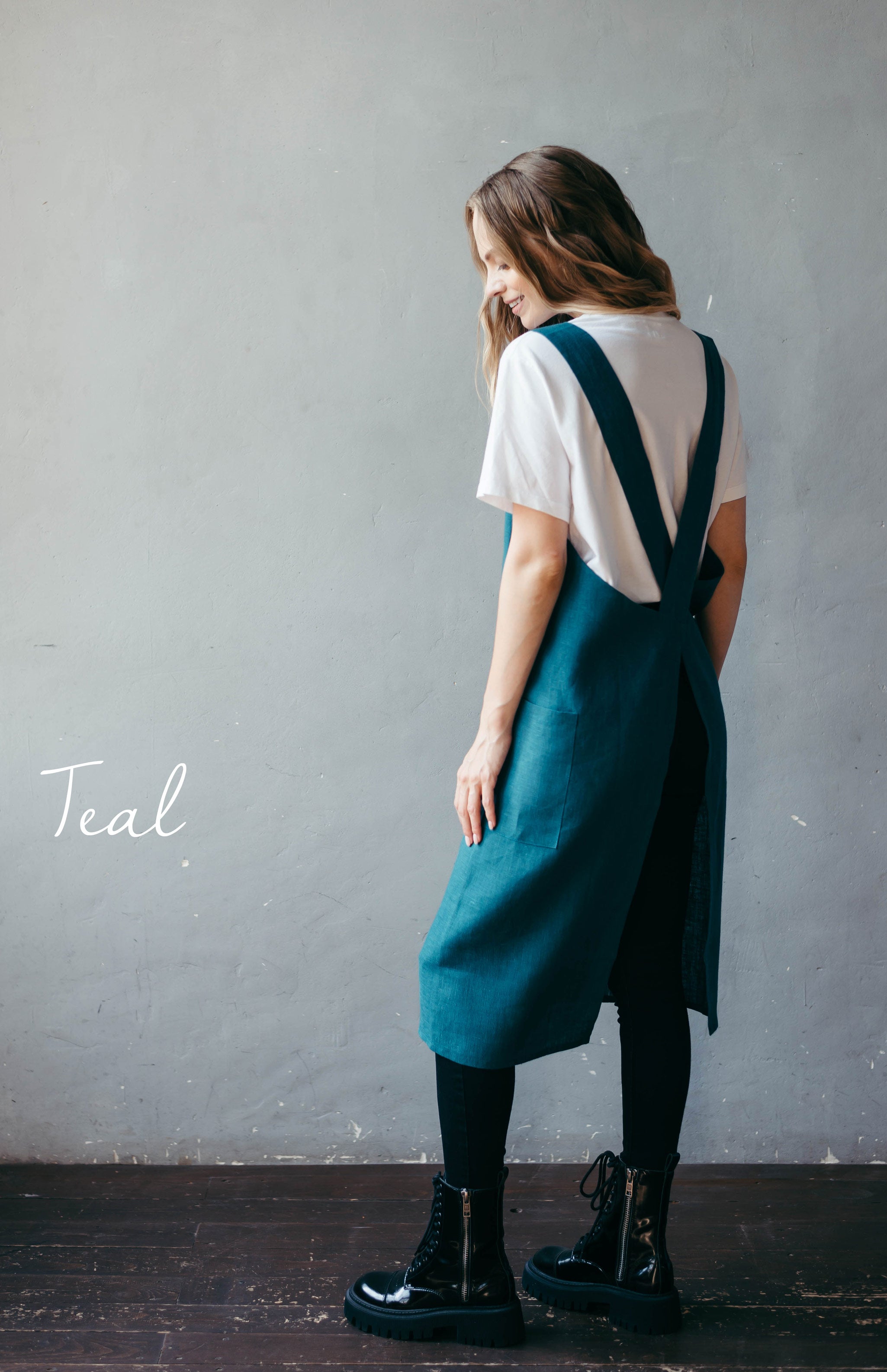 Woman in teal linen pinafore apron showing full length.