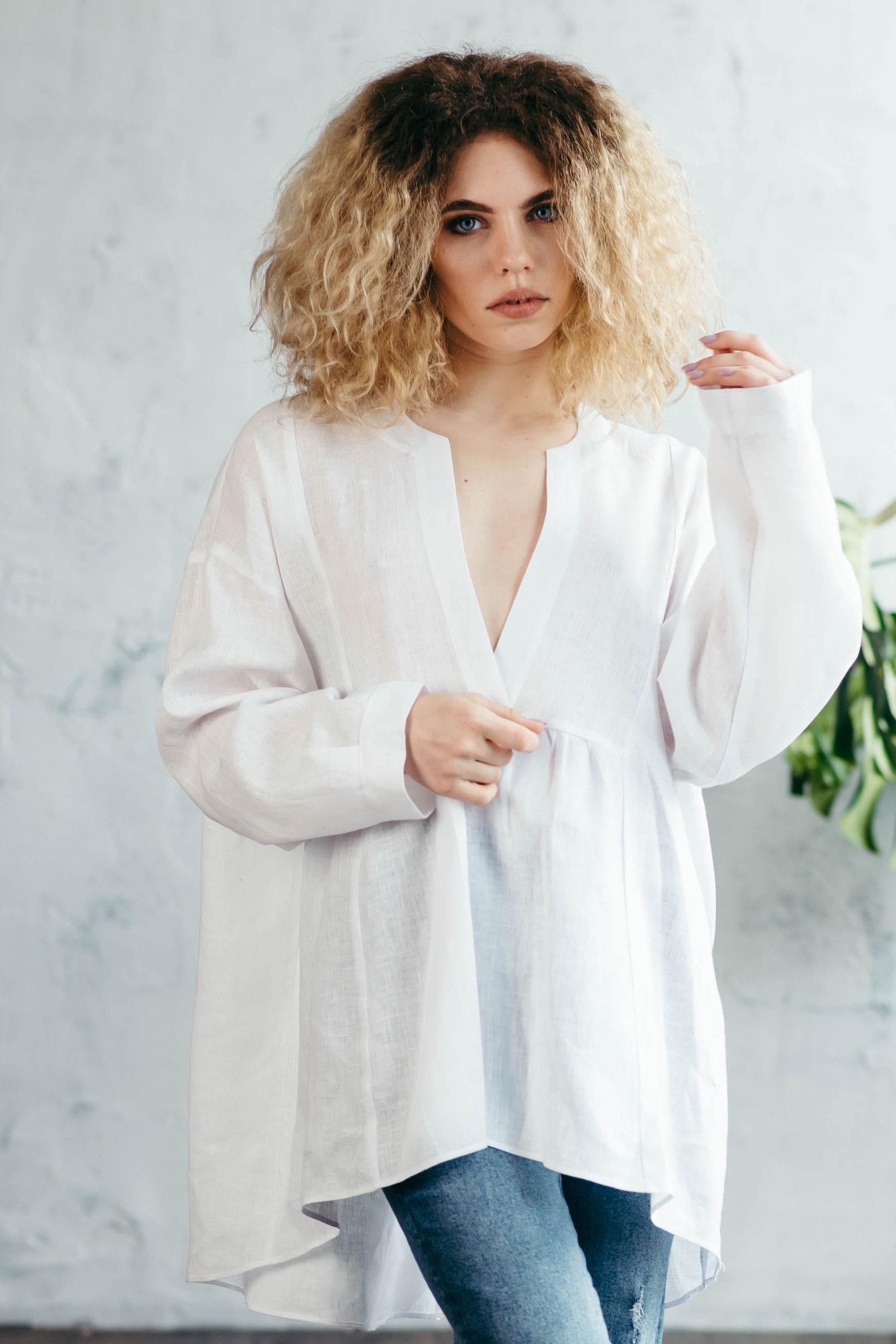 Woman wearing a white loose-fitting blouse with a blurred background