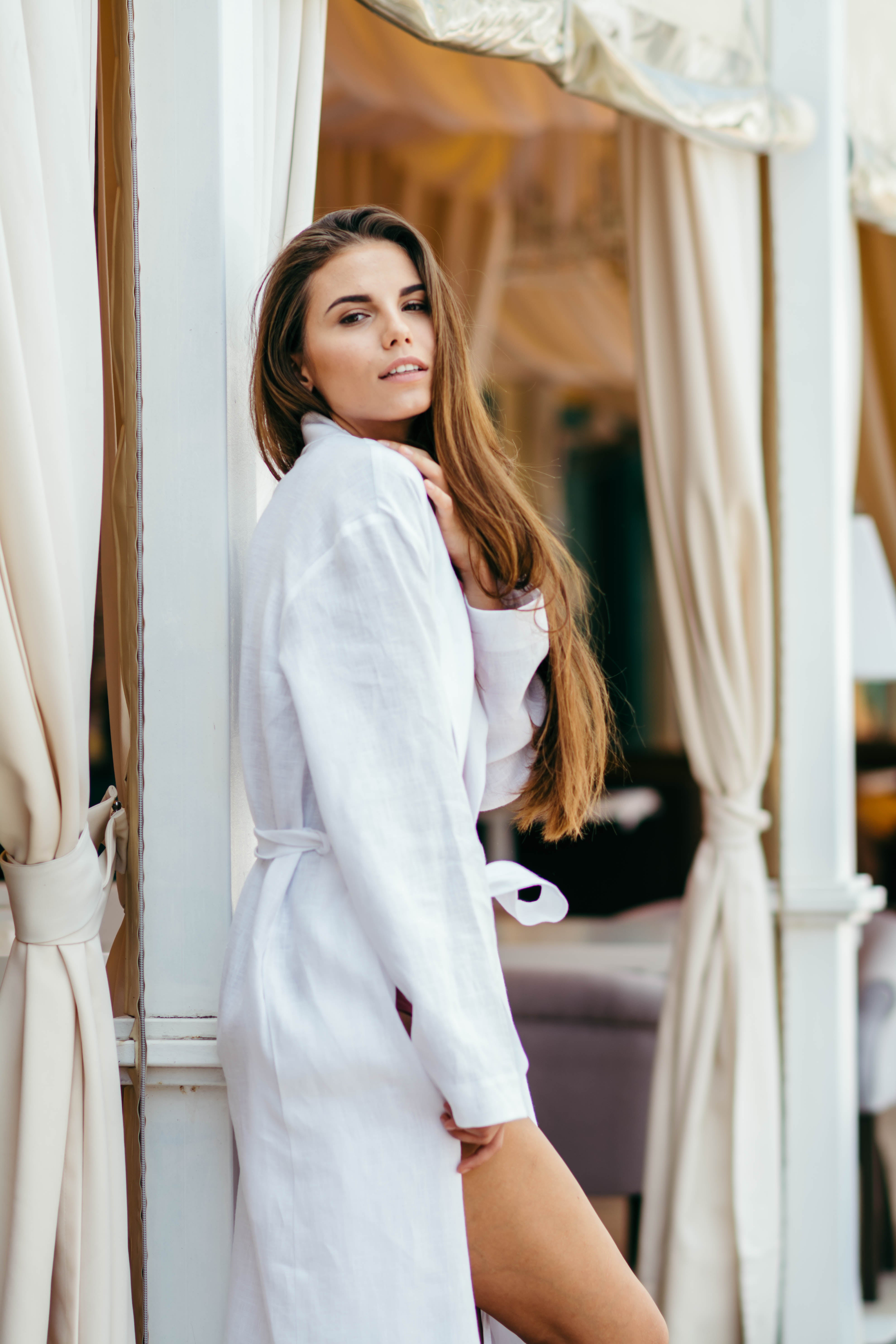 Woman in a white linen robe standing by the pool