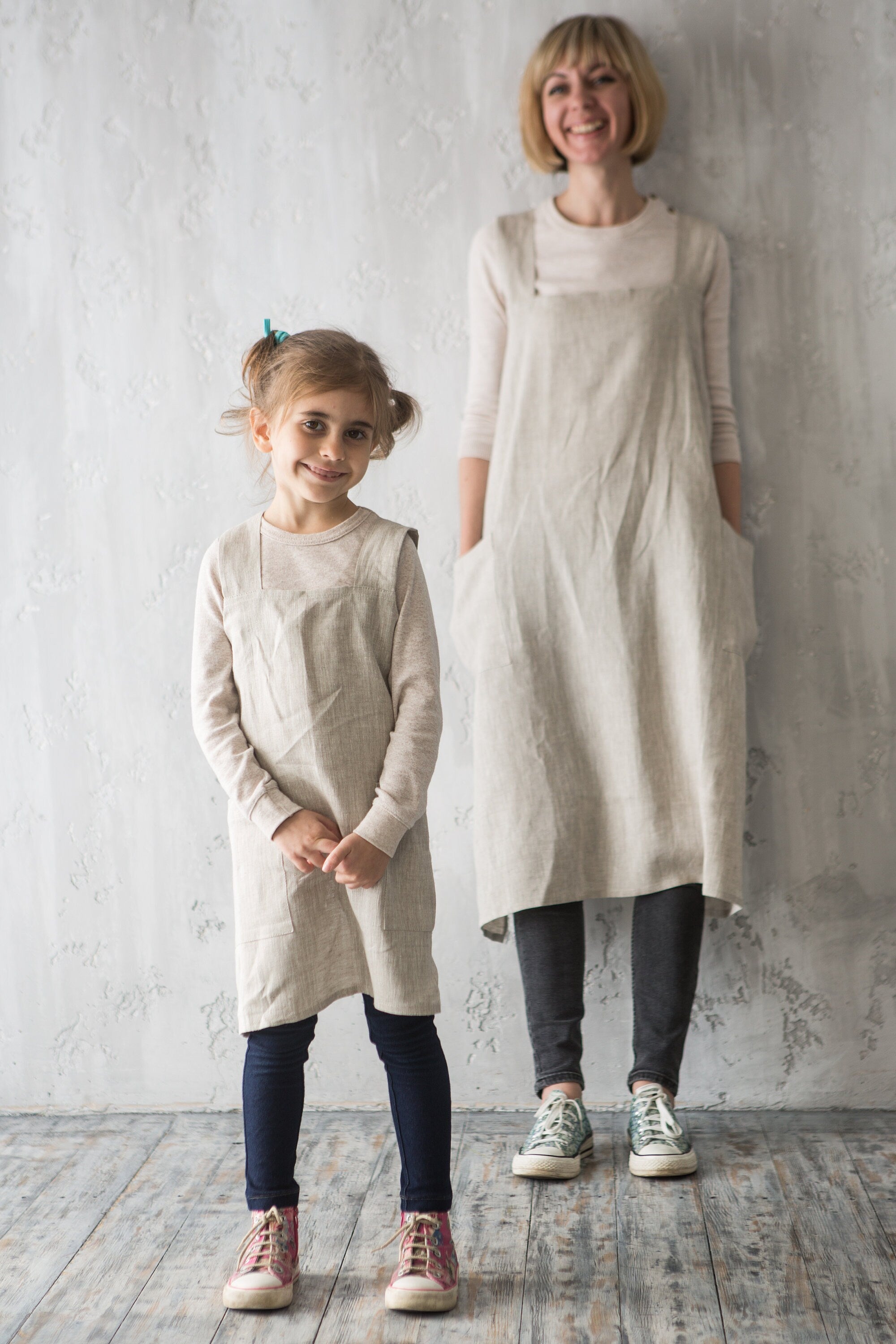 Mother and daughter wearing matching linen aprons white crafting for Christmas