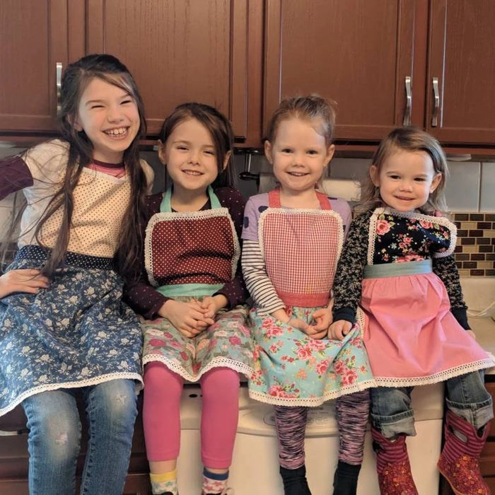 Customer wearing Kids' Personalised Aprons | Purple, Floral & Polka Dot Prints