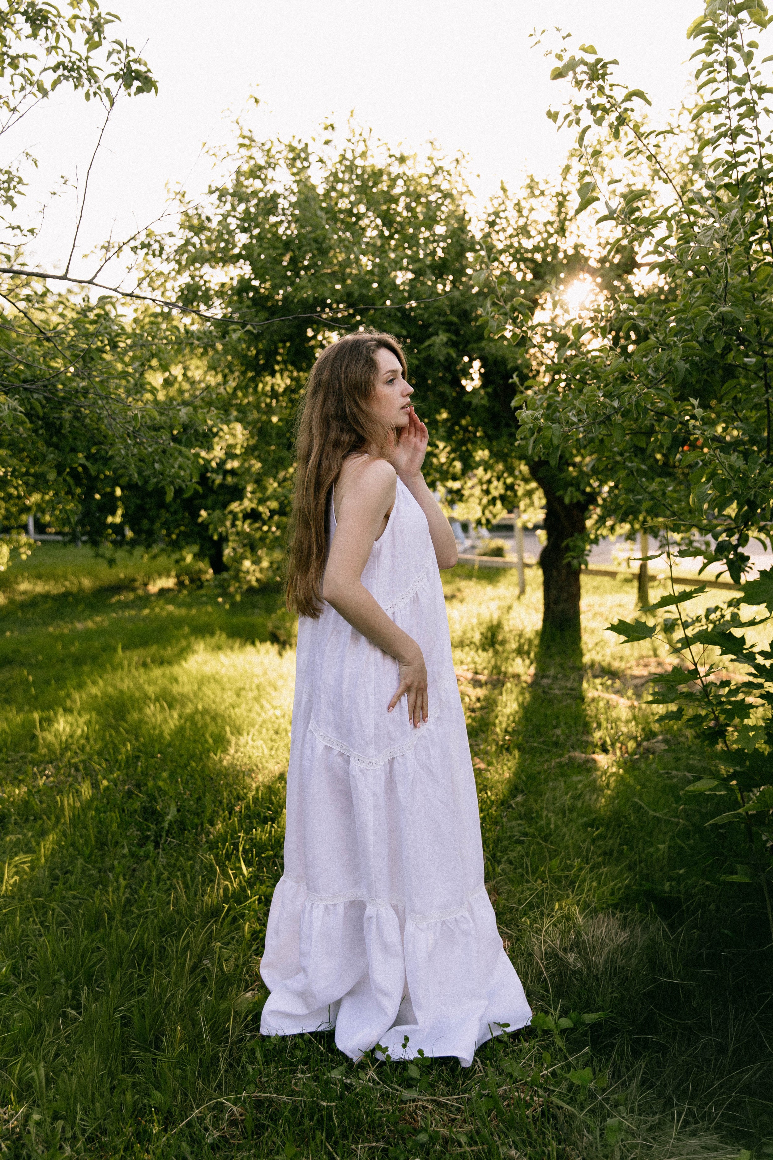 Woman in a white linen wedding dress standing in a sunlit orchard, Birmingham Brand