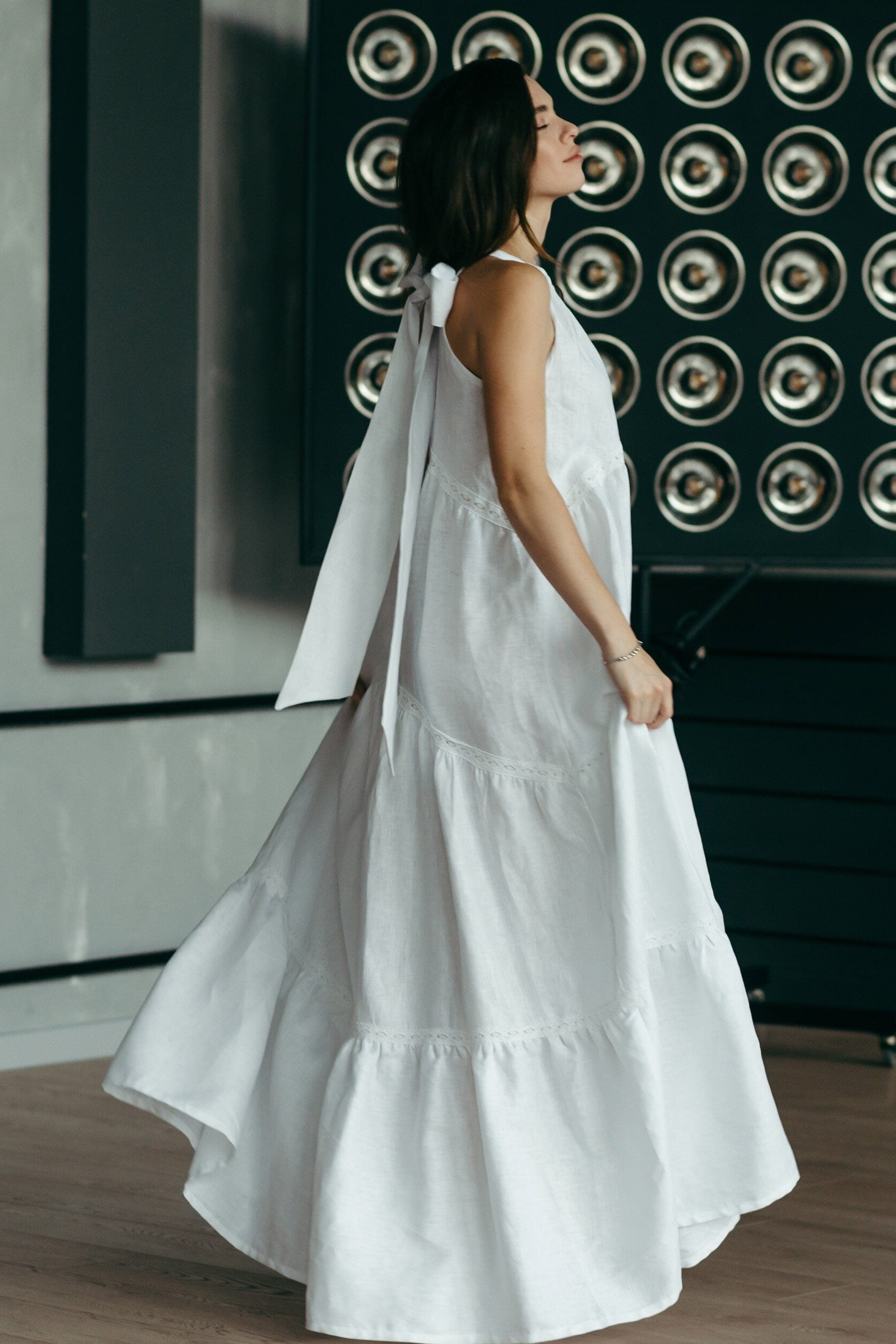 Woman in a white linen wedding dress standing in a reception room.