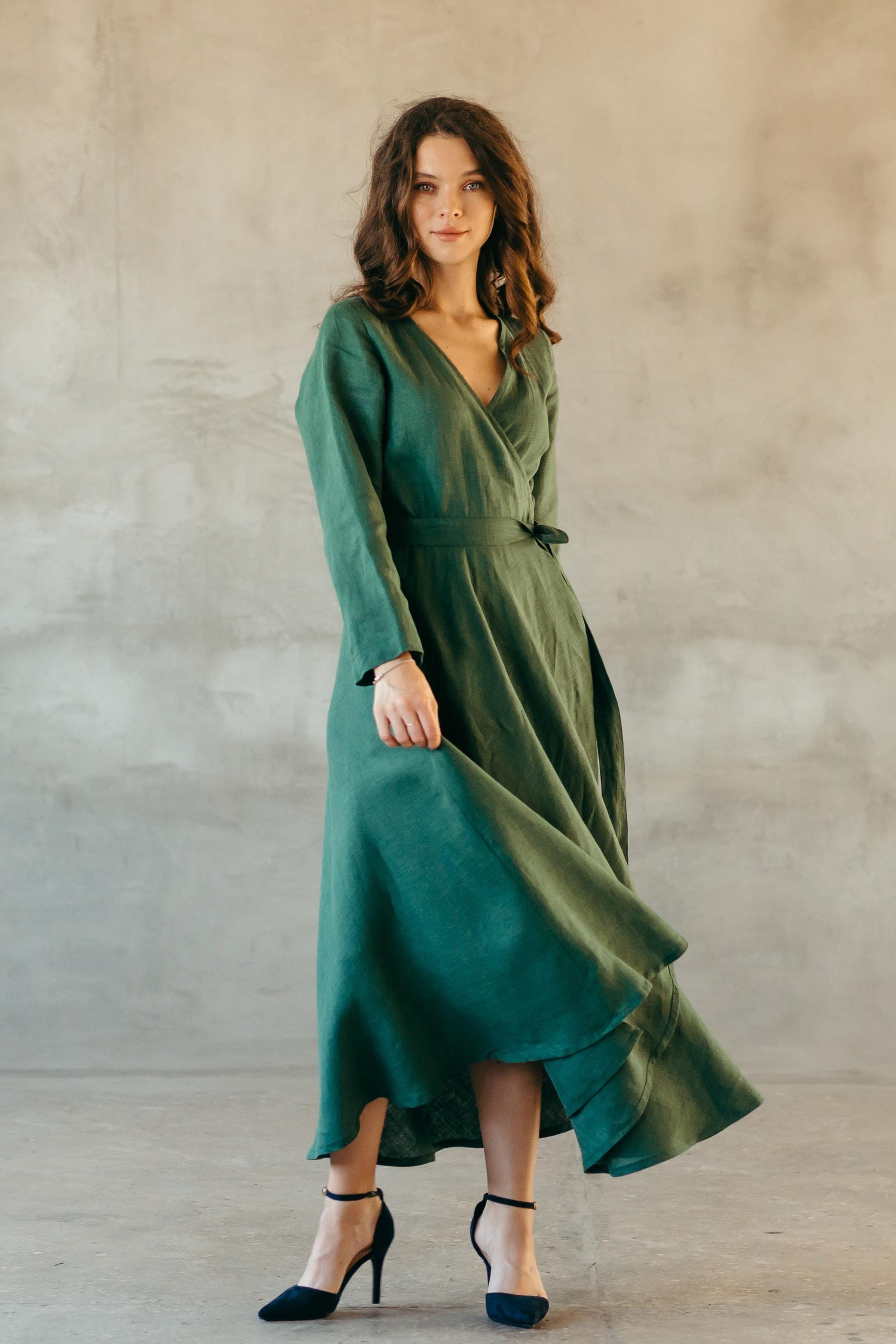 Woman wearing a green midi linen dress against a plain background