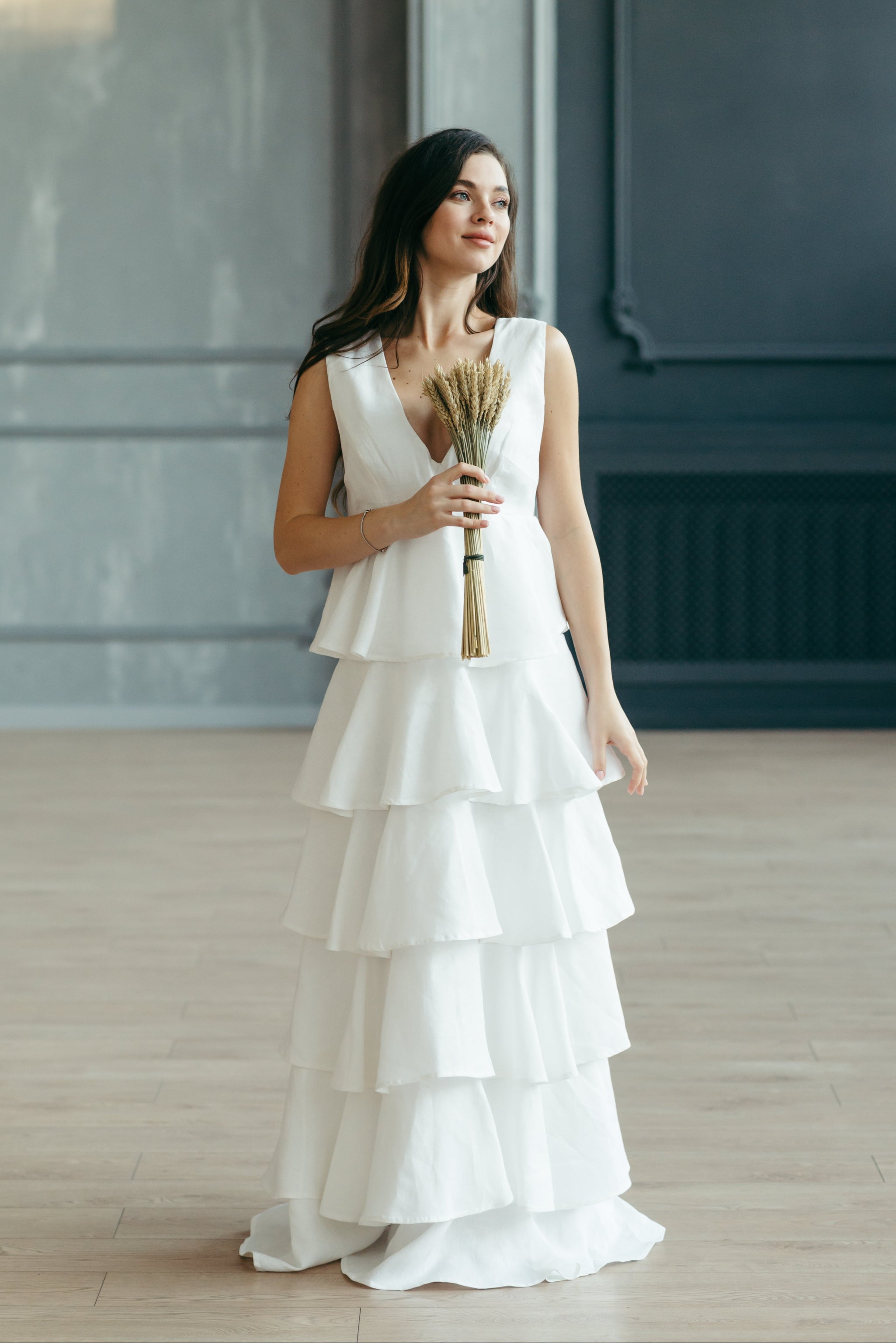 Bride is holding a dried bouquet and wearing the tiered beach wedding dress