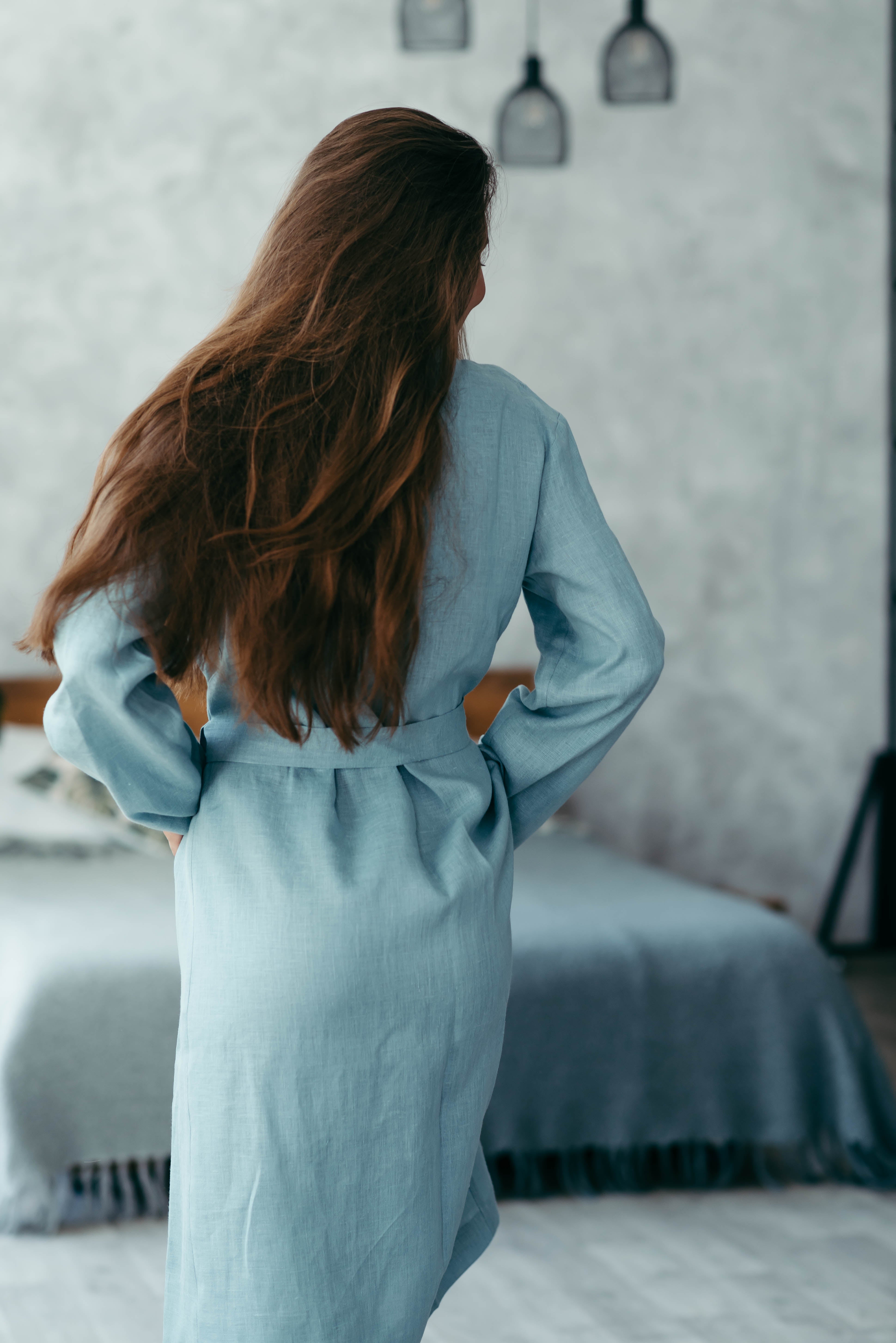 Woman in a blue dressing gown standing in a bedroom